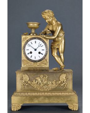 511-Reloj francés Carlos X. c. 1830. En bronce dorado con maquinaria tipo París. Esfera con numeración romana. Con representación de niño con conchas y pa