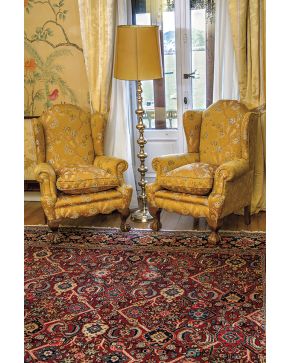 704-Pareja de sillones orejeros estilo inglés. con patas delanteras de garra sobre bola y tapicería de motivos florales sobre fondo color mostaza.