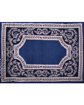560-Alfombra en lana de nudo español. diseño Luis XVI. con marcas M. Stuyck. Decoración de roleos vegetales en tonos grises sobre campo azul.. 