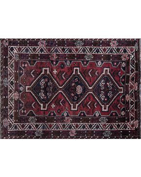 1042-Alfombra persa en lana con decoración de motivos geométricos sobre campo granate. Colores complementarios: beige y negro.
