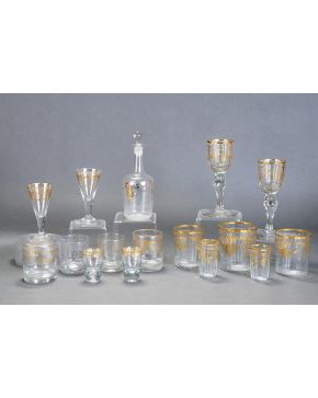 877-Lote en vidrio incoloro de La Granja formado por cinco vasos de diferentes alturas y pareja de copas en cristal facetado. Decoración dorada al fuego c