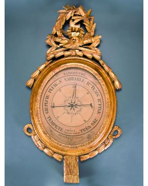 554-Barómetro francés con marco oval en madera tallada y dorada Luis XVI con copete de antorchas. aves. motivos vegetales y lazos.