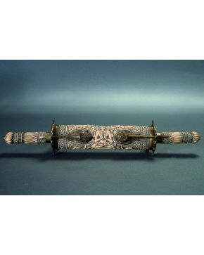 821-Arma hindú en hueso con representaciones en relieve de elementos vegetales y figuras femeninas. Con montura y aplicaciones en bronce dorado. Doble emp