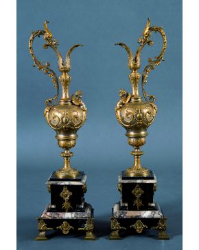 1040-Pareja de jarras decorativas frencesas en bronce dorado profusamente labrado y relevado con guinaldas y elementos vegetales. dispuestas sobre pedestal