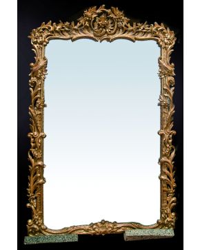 584-Gran espejo en madera tallada y dorada con profusa decoración vegetal e importante copete de guinalda. s. XIX.