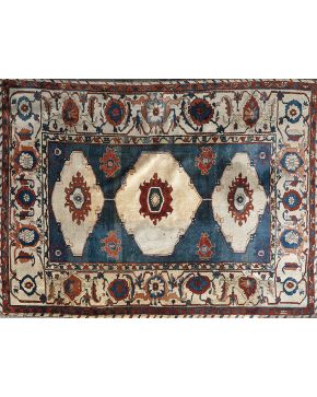 943-Alfombra en lana de campo azul con motivos geométricos en marfil. rosa. negro y naranja. Con gran cenefa perimetral en los mismos tonos.