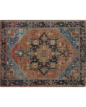 472-Elegante alfombra persa en lana. Campo rosa y medallón cental estrellado en azul marino. Con motivos geométricos y vegetales en crema. verde. marrón y
