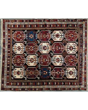 700-Alfombra en lana con campo decorado con cuatro hileras de octógonos con decoración geométrica central y triple cenefa floral sobre campo color granate