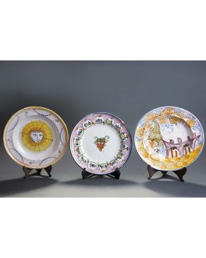 887-Lote formado por tres platos llanos con ala en cerámica de Manises. Siglo XIX. Uno de ellos con decoración de paisaje con puente y firmado en manganes