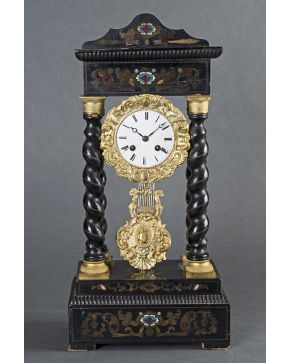 1090-Reloj de pórtico con columnas salomónicas en madera ebonizada y decoración de marquetería metálica. carey y esmalte. Esfera con numeración romana y me