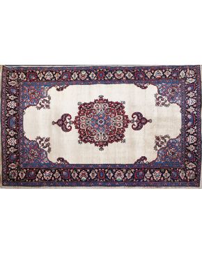 612-Alfombra persa en lana con rosetón central sobre campo beige. Decoración de motivos florales en el centro y cenefa.