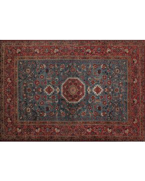 518-Gran alfombra persa en lana con profusa decoración vegetal y octógono central sobre campo azul y cenefa en granate. 