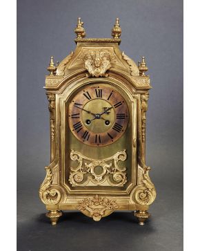 776-Reloj de sobremesa estilo Luis XIV en bronce dorado con decoración relevada de elementos vegetales. mascarón central y remate de pináculos. Esfera con