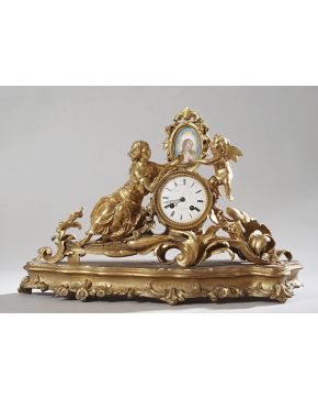 1156-Reloj de sobremesa francés de bronce dorado. fines s. XIX. Sobre una peana de madera tallada y dorada. 
