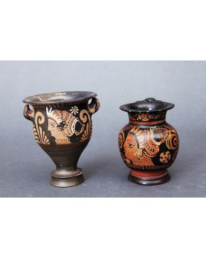 1245-Lote de dos vasijas en cerámica de inspiración griega con decoración de figuras rojas sobre fondo negro. Una de ellas tipo jarrita y la otra con dos a