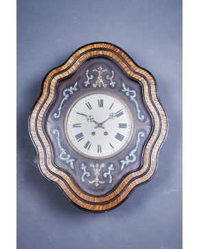 1117-Reloj ojo de buey de perfil ondulado. s. XIX. con marco en madera tallada y ebonizada con aplicaciones de madreperla. Esfera con numeración romana y m
