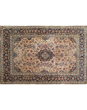 798-Alfombra persa en lana y seda con profusa decoración vegetal y floral sobre campo beige y cenefa en azul oscuro. 