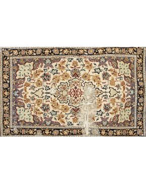 1220-Alfombra persa en lana y seda con decoración de flores y hojas sobre campo beige. Desperfectos y rotura.