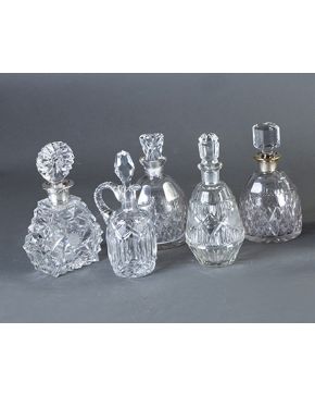 459-Lote de cinco piezas en cristal tallado: Cuatro licoreras (una con tapón deteriorado y dos de ellas con embocaduras en plateado) y jarrita con tapa.