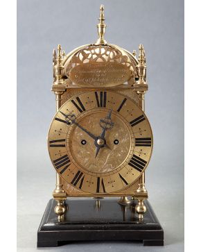 406-Reloj de linterna inglés s.XIX. En bronce dorado esfera con numeración romana. Pletina grabada y mecanismo de cuerda con llave. Sobre peana de madera.