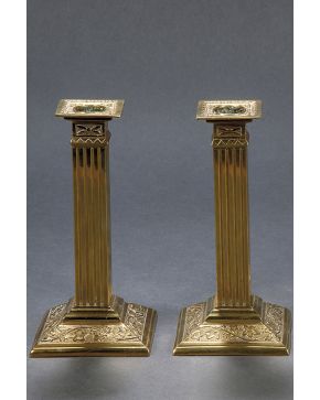 1334-Pareja de candeleros en bronce dorado con fuste en forma de columna acanalada y base con relieve de hojas.