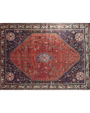 1185-Alfombra persa Shiraz en lana con tintes vegetales. Decoración geométrica y floral sobre campo azul con parte central en granate. Desgastes.