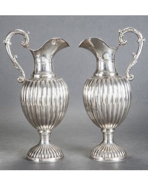 822-Elegante pareja de jarras para agua en plata española punzonada de Montejo. con decoración gallonada en pie y cuerpo y asas con motivos vegetales.