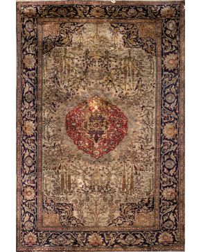 1081-Alfombra persa en lana con decoración romboidal central y motivos vegetales sobre campo verde. Cenefa en azul oscuro. 