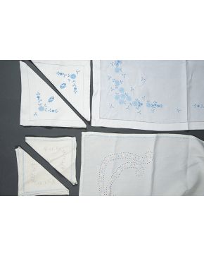 1035-Lote de dos mantelerías antiguas en hilo crudo y blanco con detalles de flores bordadas en azul y bodoques. Con 6 servilletas cada uno.