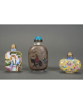 485-Lote de tres esencieros o snuff bottles. dos de ellos en bronce con esmaltes: uno a base de escenas con personajes. el segundo con flores. ambos fir