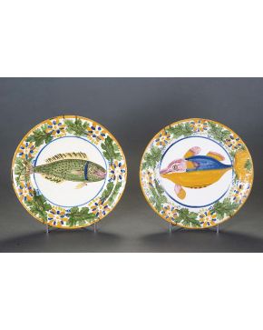 “Pareja de originales platos en cerámica levantina con firma M.A. (no identificada). S. XIX. Ala decorada con flores y hojas y centro con delfín y lenguado. Diámetro: 30,5 cm.”