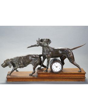 1187-Reloj de sobremesa con figuras de perros de caza en bronce pavonado. Sobre peana en madera tallada. Medidas: 45x22x78.5 cm. 