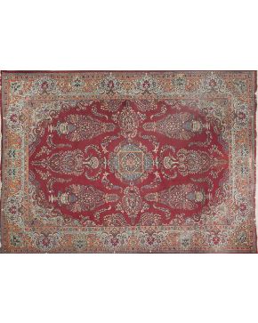 534-Importante alfombra persa en lana. Sobre campo granate. medallón central cuadrado y decoración de ánforas con ramos de flores. Gran cenefa perimetral.