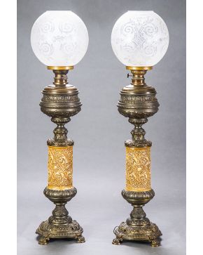 865-Pareja de lámparas tipo quinqué en metal pavonado y dorado con fuste decorado con motivos vegetales. Tulipas en vidrio al ácido.