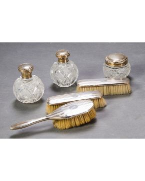 521-Juego de tocador compuesto por dos frascos y bote en cristal tallado con embocaduras en plata española y tres cepillos asociados con monturas en plata
