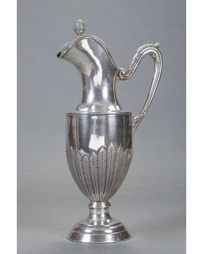 489-Elegante jarra estilo Imperio en plata española punzonada con marcas de López. Decoración de palmetas en relieve y remate de piña. Con asa decorada co