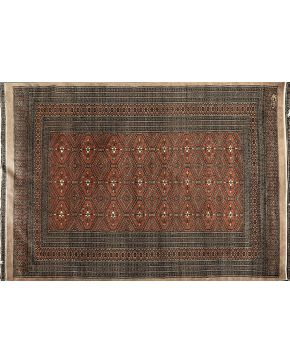 815-Alfombra oriental en lana con decoración de motivos geométricos y florales sobre campo en tonos marrones. 