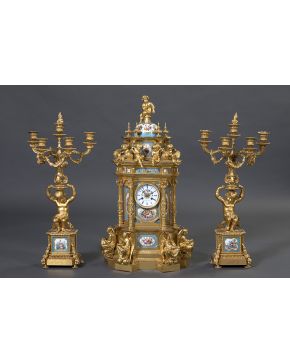 409-Importante reloj de sobremesa con guarnición de candelabros en bronce dorado y placas en porcelana esmaltada. Francia. c. 1880.