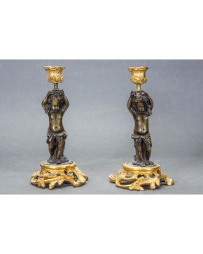 594-Pareja de candeleros estilo Luis XV en bronce dorado y pavonado. Francia. s. XIX. Con fustes de querubines.