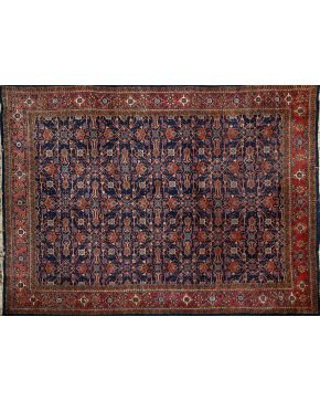670-Alfombra persa en lana con decoración floral y vegetal sobre campo azul oscuro y cenefa en tono rojizo. 