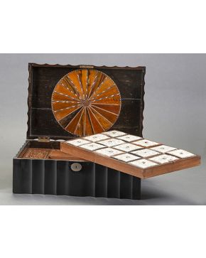 989-Caja inglesa. s. XIX. en madera de ébano. Al interior compartimentada con dos bandejas. Tapas en hueso grabado y decoración de marquetería. 