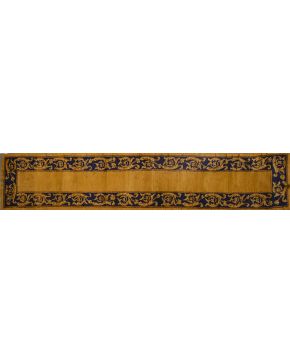 1185-Alfombra de pasillo en lana de nudo español sobre campo marrón y cenefa decorada con roleos vegetales sobre campo azul oscuro.