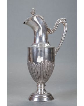 457-Elegante jarra estilo Imperio en plata española punzonada con marcas de López. Decoración de palmetas en relieve y remate de piña. Con asa decorada co