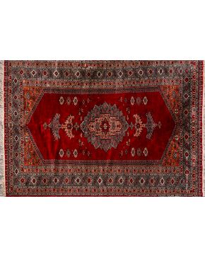 495-Alfombra persa en lana con decoración floral sobre campo granate y cenefas en tonos marrones.