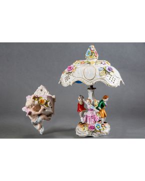 644-Lote formado por lámpara y aplique-violetero en porcelana centroeuropea. Con decoración de personajes y amorcillos. Faltas en lámpara.