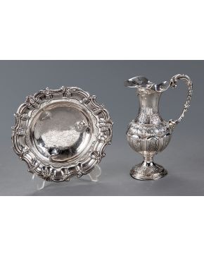 663-Lote en plata punzonada formado por: jarra y frutero sobre tres patitas con marcas de Montejo. Decoración cincelada y grabada de flores. Abolladuras. 