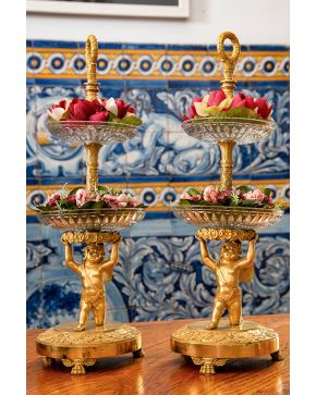 607-Pareja de elegantes centros de mesa Imperio. s. XIX. realizados en bronce dorado y cristal moldeado y tallado. Sobre pies de garra. con fustes de ange