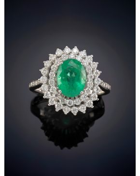 507-ELEGANTE SORTIJA CON UNA ESMERALDA CENTRAL CON DOS ORLAS DE BRILLANTES sobre una montura en oro blanco de 18K.