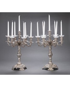 1026-Pareja de grandes candelabros de 7 luces en plata española punzonada con marcas de Montejo. Decoración a base de tornapuntas. flores y motivos vegetal