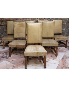782-Juego de ocho sillas estilo Luis XIII. En madera tallada. con chambrana en H y tapicería en cuero en su color tachueladas.